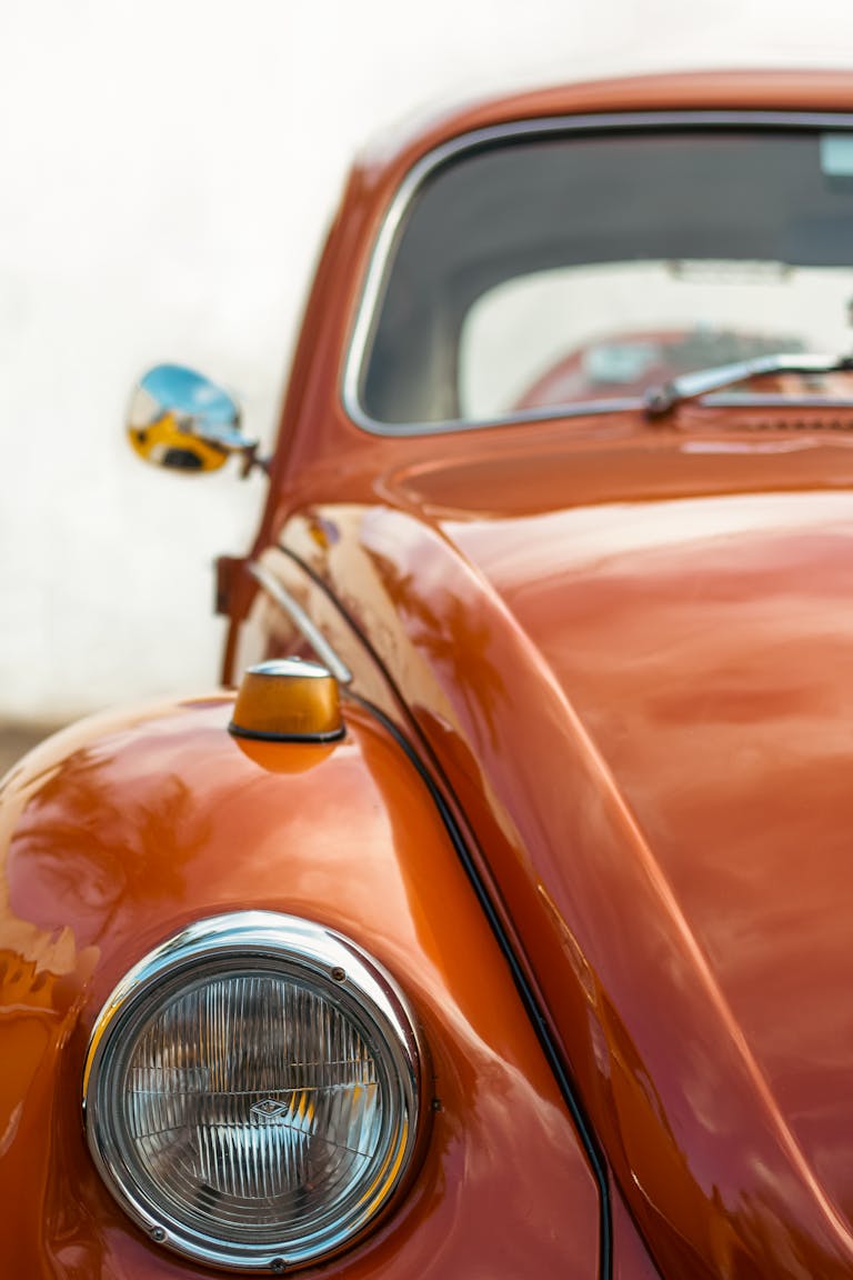Close-up of a classic orange Volkswagen Beetle car with chrome details, perfect for vintage auto enthusiasts.