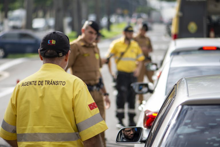 Traffic agent in bright uniform managing vehicles on a busy Londrina street.