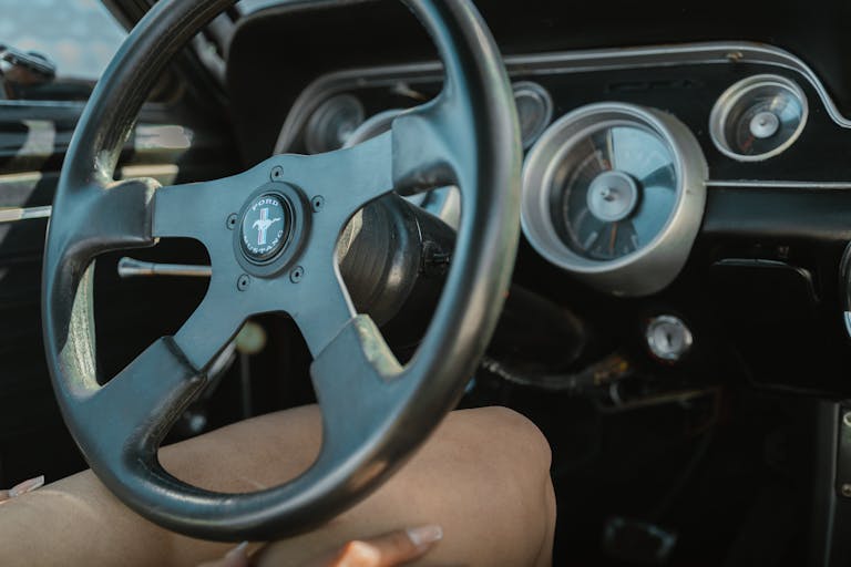 Close-up of a vintage Ford Mustang steering wheel and dashboard showcasing retro car design.