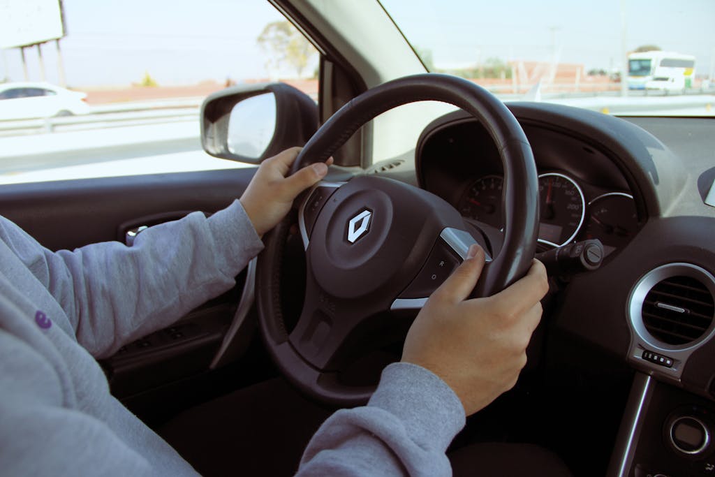 Imagen actual: Close-up of hands on steering wheel while driving through Mexico in daylight.