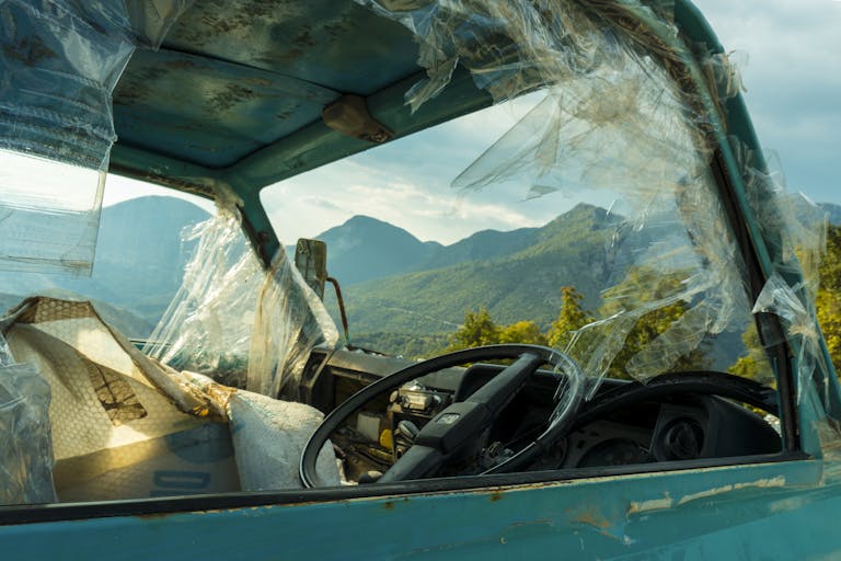 Old rusty truck with broken windows in front of mountain landscape, symbolizing decay.