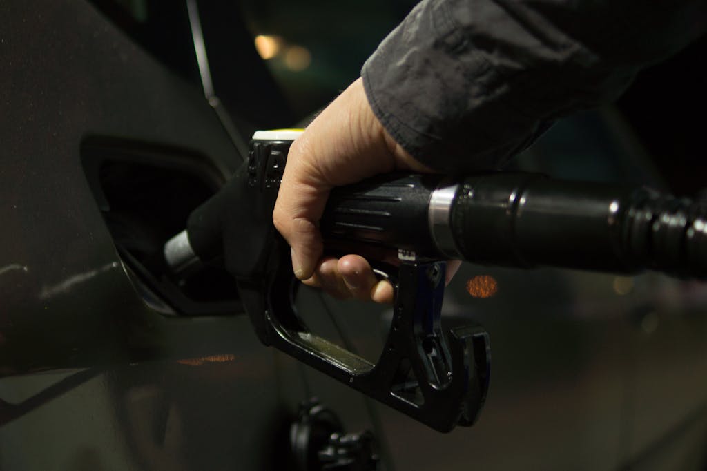 Close-up of a person refueling a car at a gas pump during night.