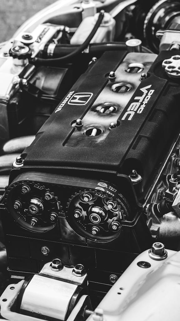 Imagen actual: Detailed view of a Honda VTEC engine showcasing metal parts and gears in monochrome.