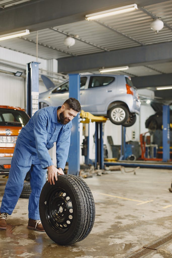 Imagen actual: Mechanic handling a tire in a busy automotive repair workshop.