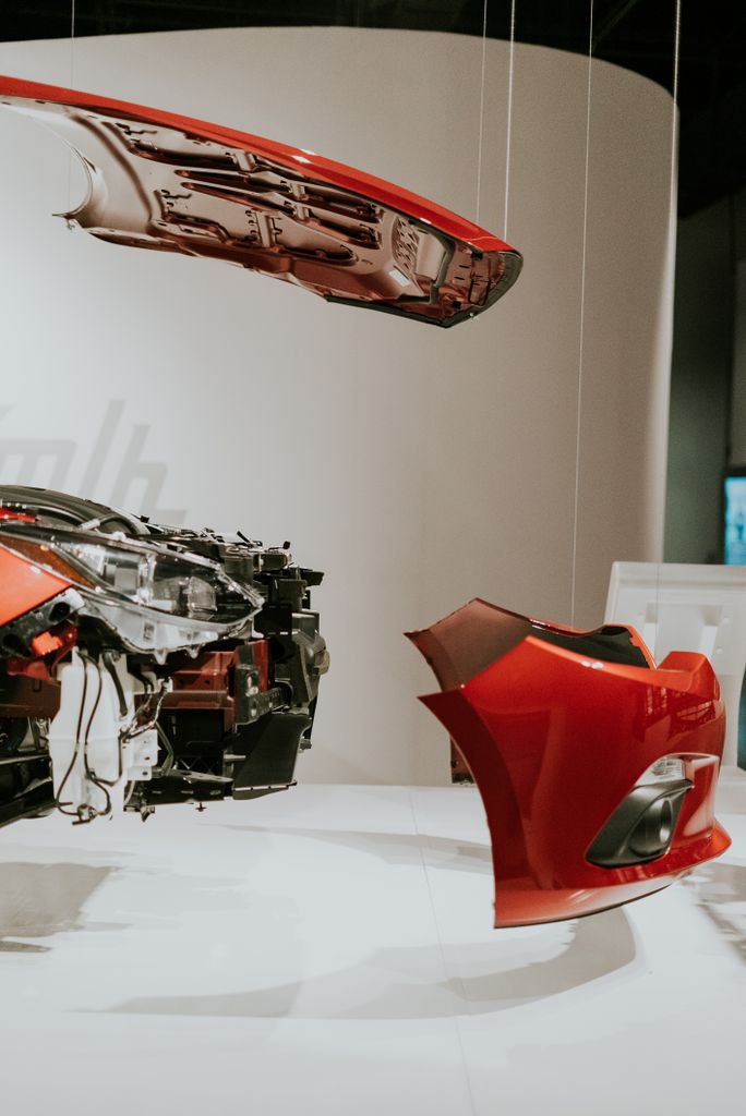 Imagen actual: A detailed view of disassembled car parts hanging in a modern exhibit setup.